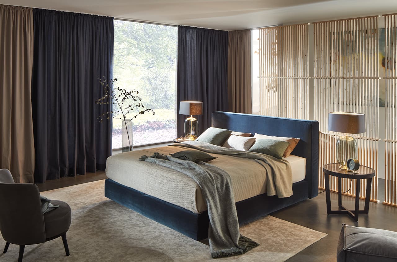 Stilvolles Schlafzimmer mit blauem Polsterbett.